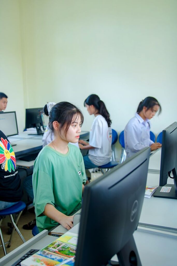 Group of students studying in a computer lab, focused on teamwork and education.