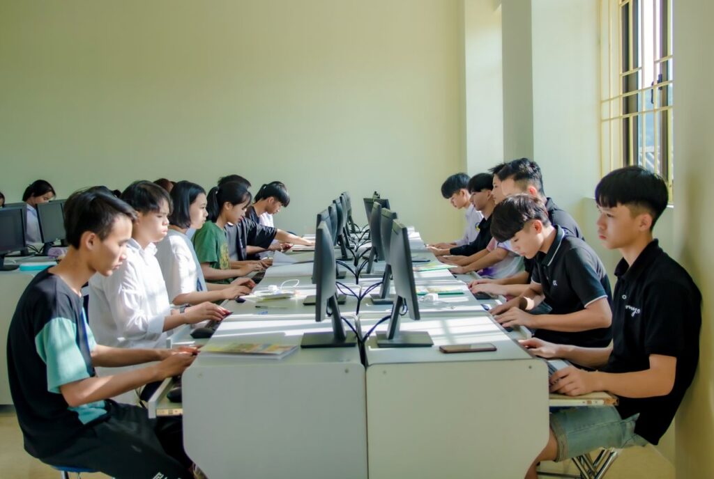 A group of students in a classroom focused on computer screens, fostering digital education.