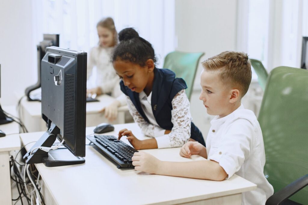 Diverse children working together on computers in a modern school setting.